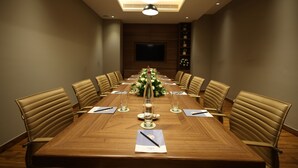 A conference room with a long table, chairs, a floral centerpiece, and a flat-screen TV on the wall. - Fortune Park, East Delhi - Member ITC Hotels' Group (New Delhi)