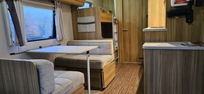 A compact RV interior with a kitchenette, a small dining table, and seating areas. - Rostrevorvalley Caravan Experience Private Hottub (Newry)