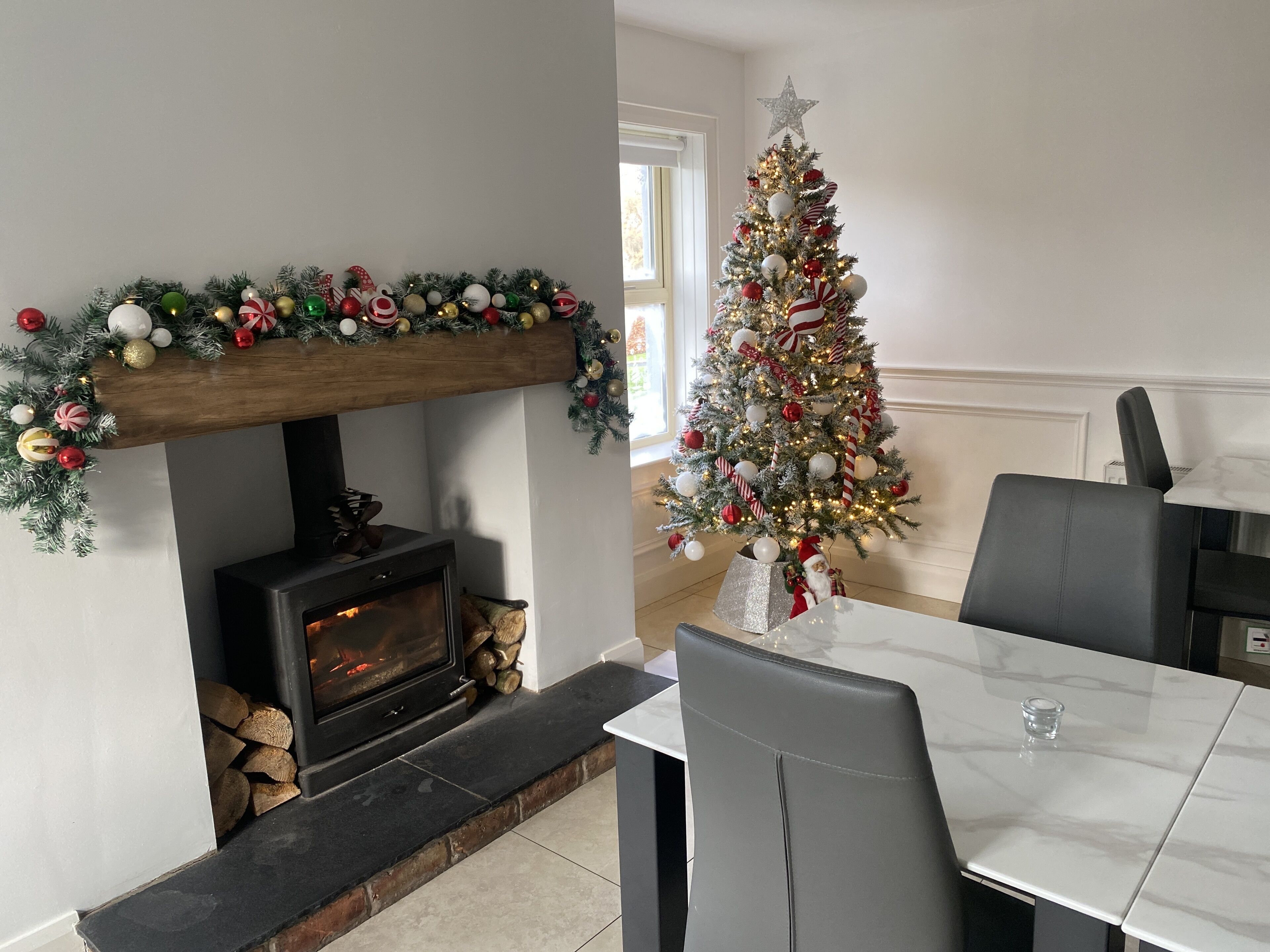 A dining area with a fireplace, a Christmas tree, and a modern table and chairs.