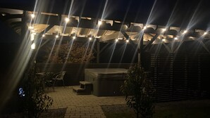 An outdoor patio area with a wooden pergola, string lights, a hot tub, and a brick pathway. - Rostrevor Valley 6-br, Sleeps 20 w/ Hot Tub & View (Newry)