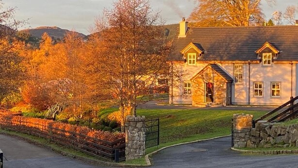 A two-story house with a stone entrance gate, a well-maintained lawn, and a driveway leading to the front door. - Rostrevor Valley 6-br, Sleeps 20 w/ Hot Tub & View (Newry)