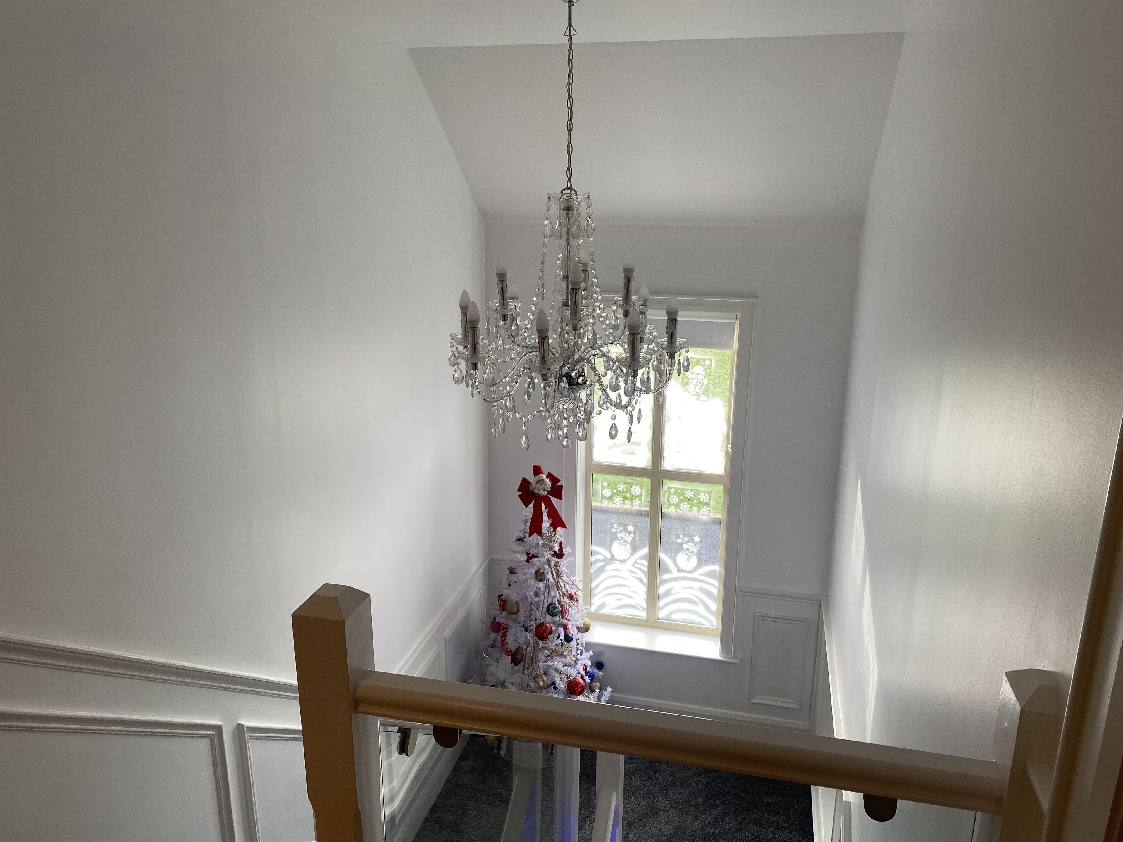 Un escalier orné d’un lustre et d’un sapin de Noël décoré.