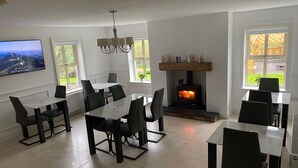 A dining area with a fireplace, a chandelier, and a TV mounted on the wall. - Rostrevor Valley 6-br, Sleeps 20 w/ Hot Tub & View (Newry)