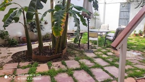 A patio area with a round table and chairs, surrounded by potted plants and a small garden.