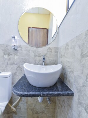 Un baño con lavamanos blanco, un espejo y un inodoro.