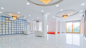 Eine großzügige Lobby mit Marmorboden, weißen Sofas, einer blauen Glasabtrennung und Kristalllüstern.
