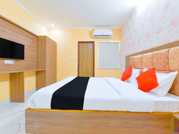 A neatly made bed with white and black bedding, a wooden headboard, and orange pillows.