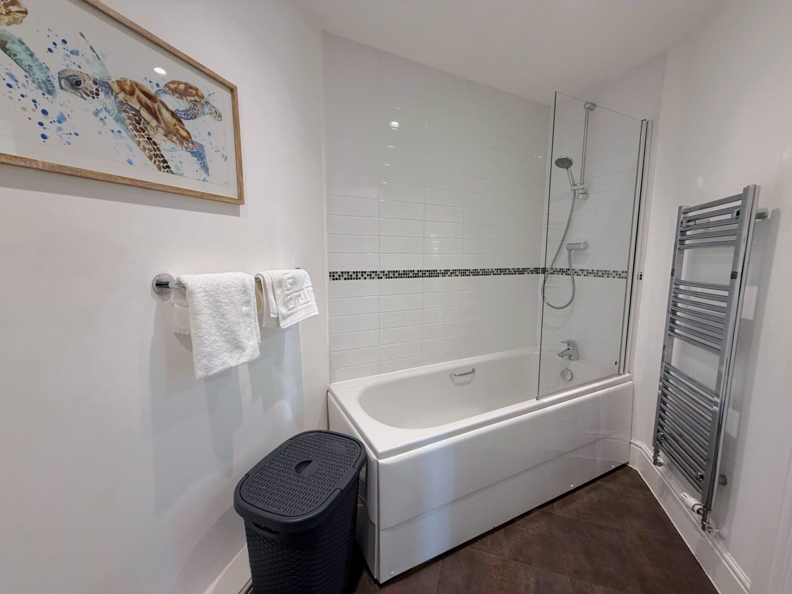 A bathroom with a bathtub, shower, and a towel rack.