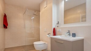 A modern bathroom with a toilet, sink, and shower area.