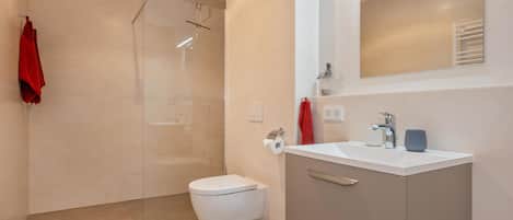 Un baño moderno con inodoro, lavamanos y zona de ducha.