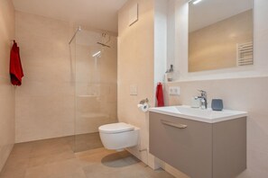 Une salle de bain moderne équipée de toilettes, d’un lavabo et d’un espace douche.