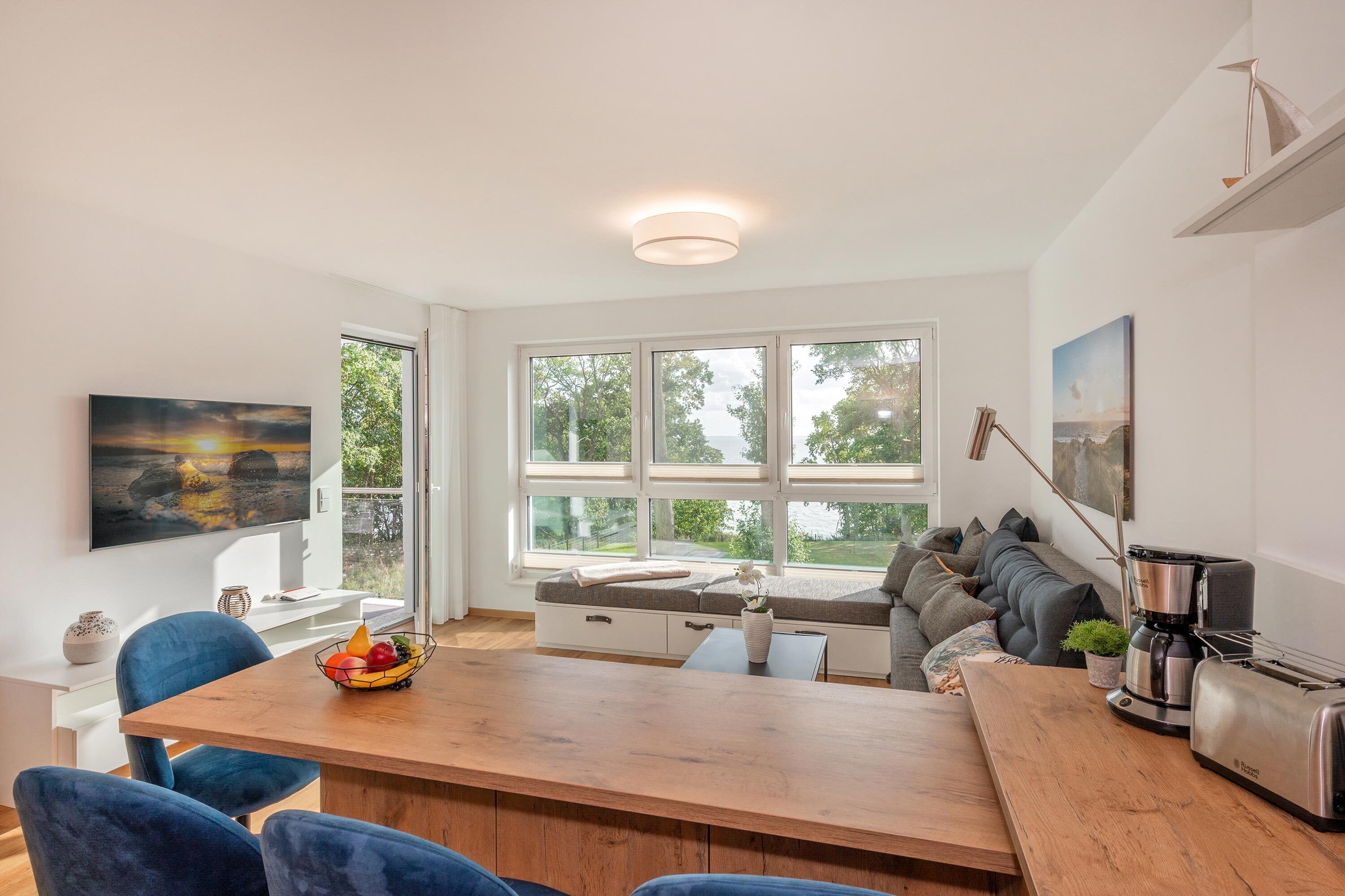 A modern kitchen with a wooden dining table, blue chairs, and a built-in bench with cushions.