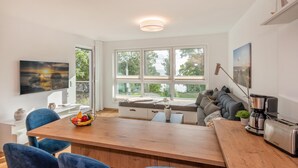 A modern kitchen with a wooden dining table, blue chairs, and a built-in bench with cushions. - "exklusives 61m² Apartment mit Haff-blick Ruhige Lage Balkon & Wlan Stellp (Zirchow)