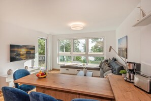 A modern kitchen with a wooden dining table, blue chairs, and a built-in bench with cushions. - "exklusives 61m² Apartment mit Haff-blick Ruhige Lage Balkon & Wlan Stellp (Zirchow)