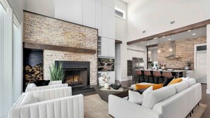 A modern living room with a fireplace, sofas, and a kitchen area.
