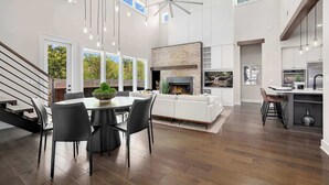 A modern interior with a dining area, fireplace, kitchen, and a staircase.