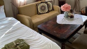 A hotel room with a bed, a sofa, a coffee table, and a window with curtains.