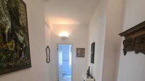 A hallway with a wooden floor, a white wall, and a door leading to a bathroom. - Casa Stefania by PortofinoVacanze (Rapallo)