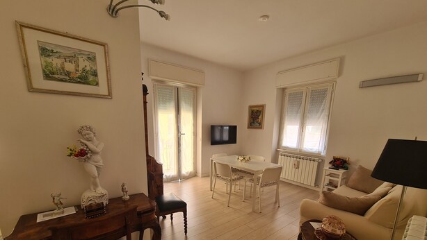 A living room with a wooden dining table, a sofa, and a TV. - Casa Stefania by PortofinoVacanze (Rapallo)