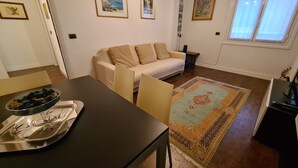 A living room with a sofa, a dining table with chairs, a rug, and framed pictures on the wall. - Casa Stefania by PortofinoVacanze (Rapallo)