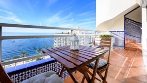 A balcony with a wooden table, white cushions, and a white lantern. - Penthouse Duplex with Panoramic Sea Views (Marbella)