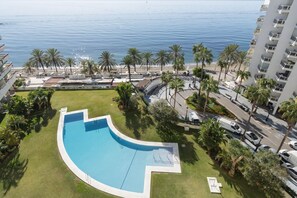 A swimming pool with a curved edge, surrounded by palm trees and a view of the ocean. - Penthouse Duplex with Panoramic Sea Views (Marbella)
