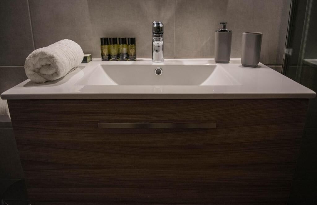 Ein Badezimmer mit einem großen weißen Waschbecken, einem Handtuch und Toilettenartikeln.