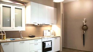 A compact kitchen with white cabinets, a stove, and a sink. - Chic and Minimal apartment close to Thissio Metro (Athina)