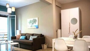 A modern living room with a sofa, coffee table, and dining area with chairs. - Chic and Minimal apartment close to Thissio Metro (Athina)