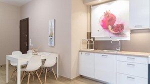 A modern kitchen with white cabinetry, a white countertop, and a pomegranate painting above the sink. - Chic and Minimal apartment close to Thissio Metro (Athina)