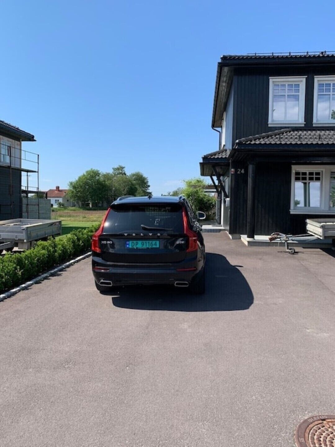 A black SUV parked in front of a house with a number 24 sign.