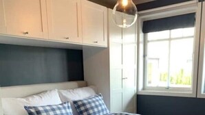 A bedroom with a bed, checkered pillows, a black throw, and a hanging light fixture. - 3-roms Leilighet på Gateplan i Landlige Omgivelser (Vestfold og Telemark,)