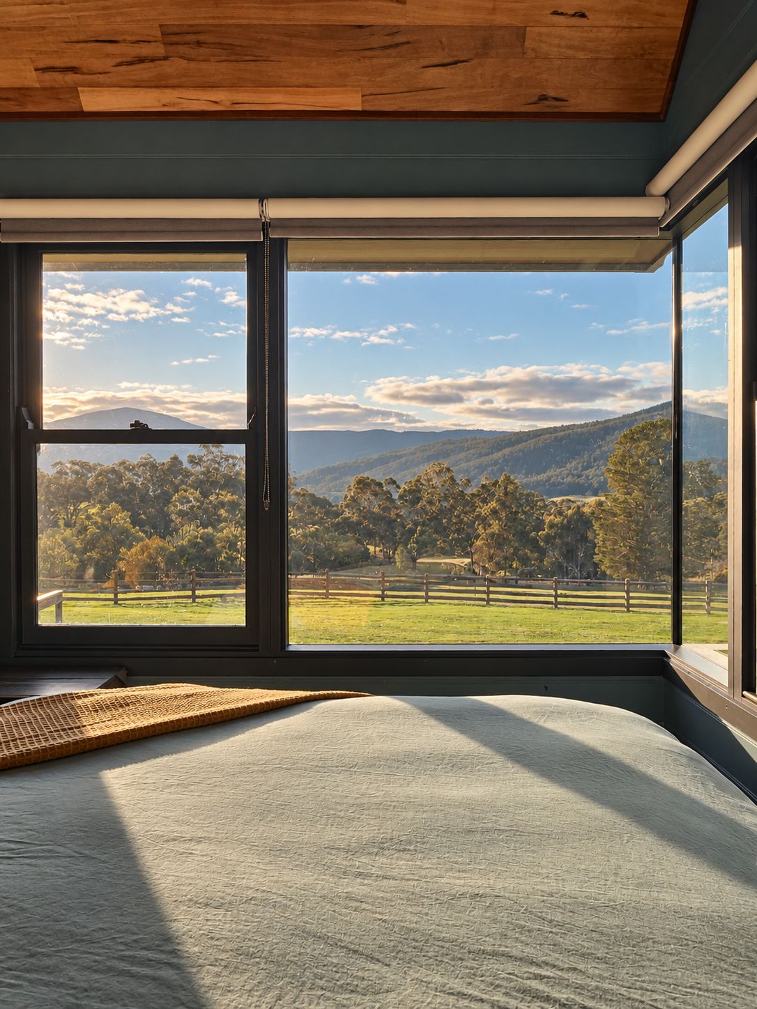 Ein Zimmer mit großem Fenster und Blick auf eine Landschaft mit Bäumen und Hügeln.