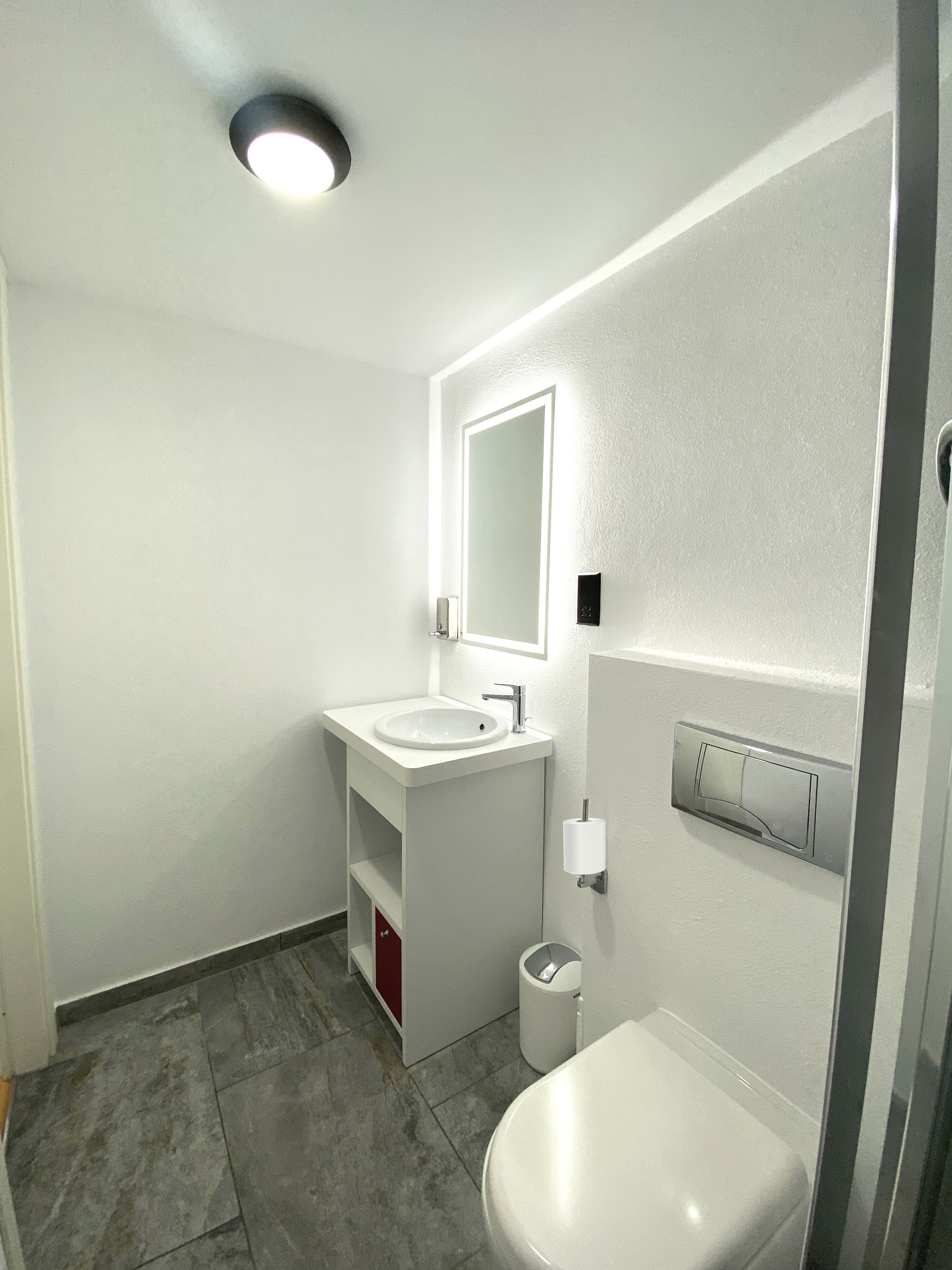 Een moderne badkamer met een witte wastafel, een spiegel en een toilet.