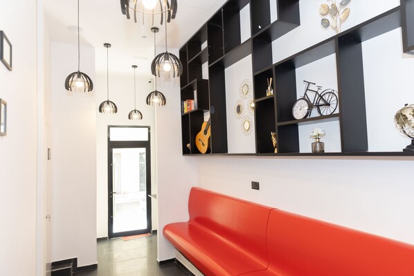 A modern interior with a red bench, black and white shelving, and hanging pendant lights. - Citizen suites (Sliema)