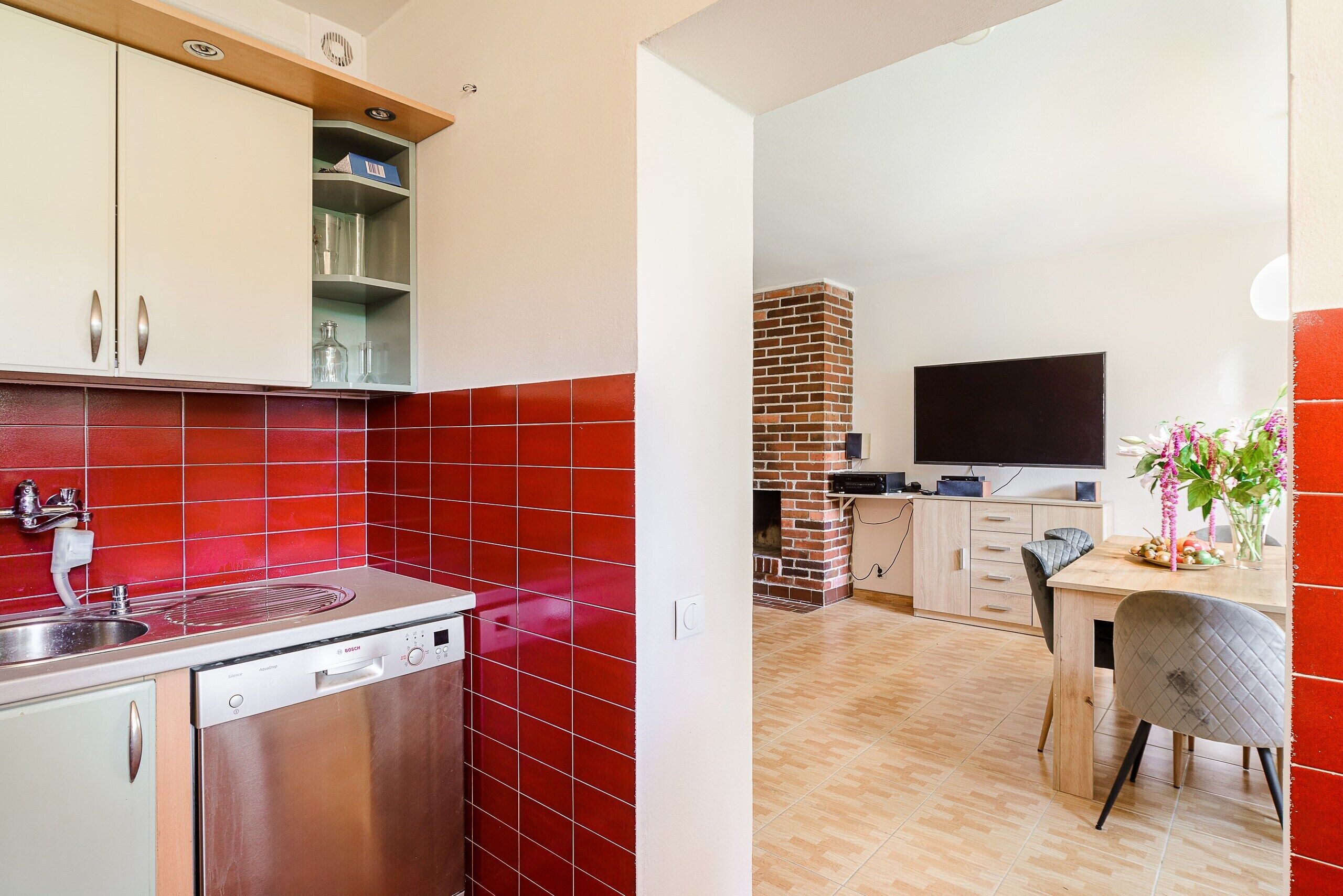 Una cocina moderna con baldosas rojas, lavavajillas y un horno de ladrillo.