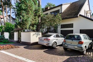 A two-story house with a paved driveway and a parked car. - Wawer Juhasów (Warsaw)