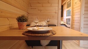 Una mesa de madera con un plato, dos copas de vino y una pequeña planta en maceta.