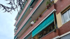 A multi-story building with balconies, some with plants. There are closed garage doors at the ground level. - Casa Thea by PortofinoVacanze (Rapallo)