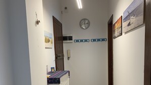 A hallway with a stone floor, a clock on the wall, and a door with a wooden frame. - Casa Thea by PortofinoVacanze (Rapallo)