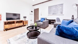 Un salon moderne avec un canapé gris, un meuble TV en bois et un téléviseur à écran plat.