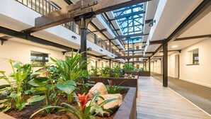 Un vaste atrium intérieur doté d’un haut plafond, de poutres en bois et de plusieurs niveaux.