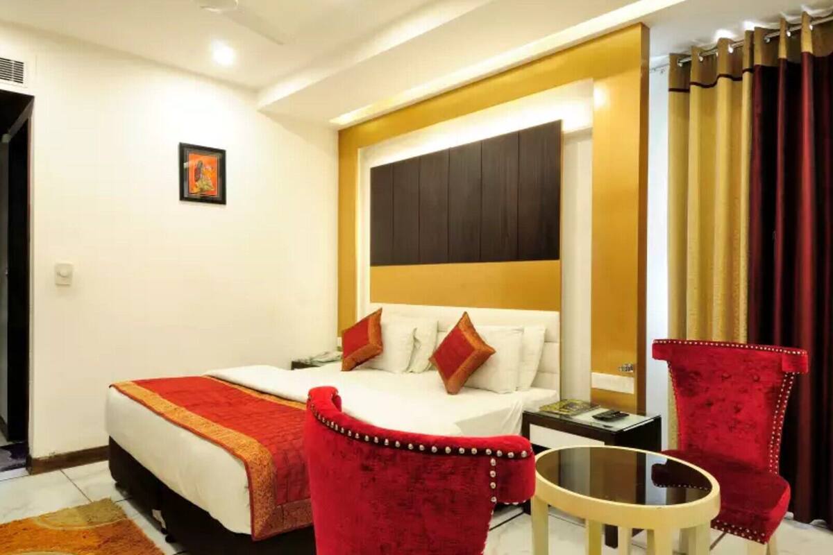 A hotel room with a bed, a small table, two chairs, a nightstand, and a picture on the wall.