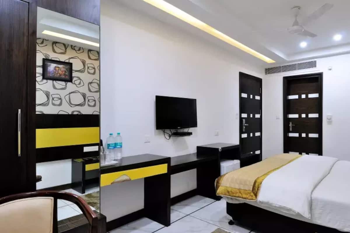 A modern hotel room with a bed, desk, and television.