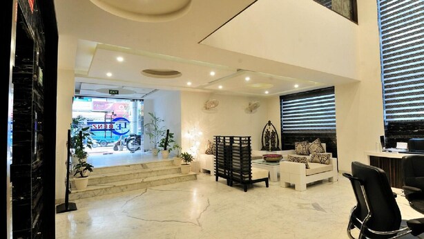A modern hotel lobby with a reception desk, seating area, and a staircase leading to an upper level. - Hotel Lee Benz (New Delhi)