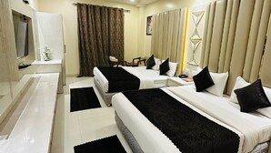 A hotel room with two single beds, a TV, a desk, and a ceiling fan. - Hotel Lee Benz (New Delhi)