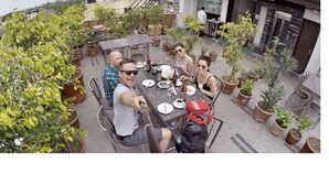 A group of people dining at an outdoor table surrounded by potted plants. - Hotel Lee Benz (New Delhi)