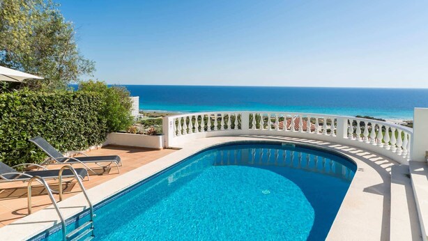 Ein Pool mit geschwungener Kante, weißer Brüstung und Blick aufs Meer.