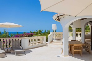 A terrace with a table and chairs, a white umbrella, and a view of the sea. - Villa Treya - Star property, stunning views (San Jaime Mediterráneo)