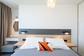 Una habitación de hotel moderna con cama, mesitas de noche y un buró.